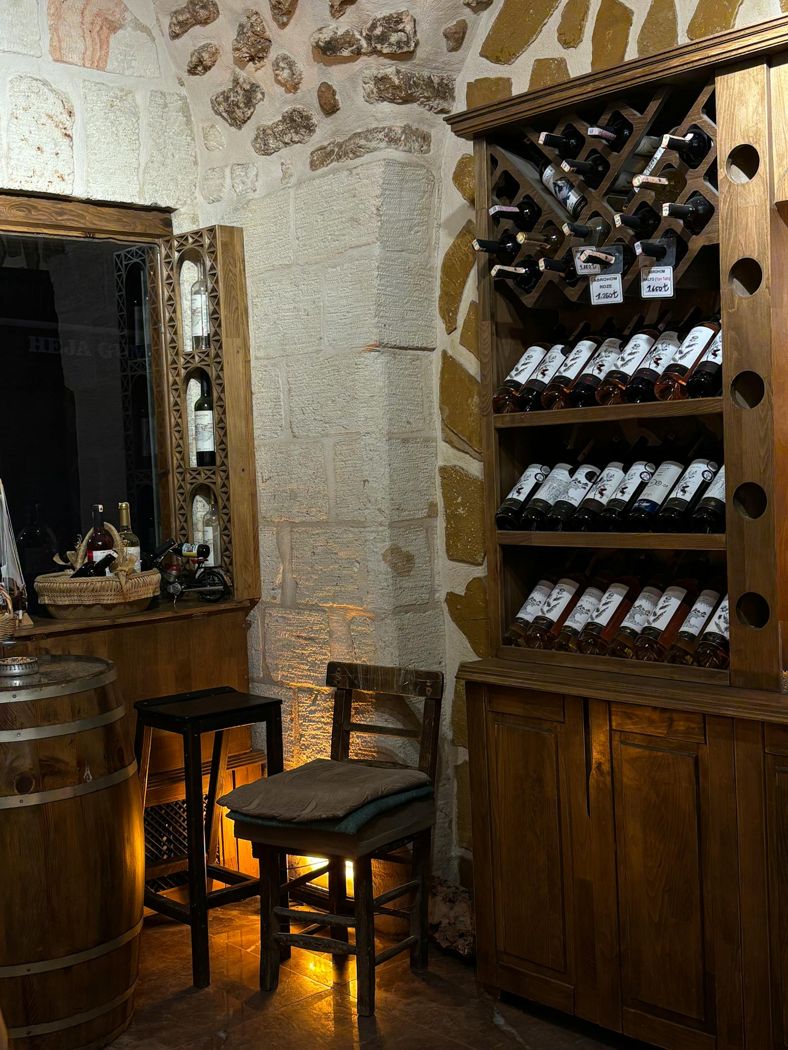 The Vermora cellar at dusk — French oak barrels stacked under low warm light, a small wooden table set for two.